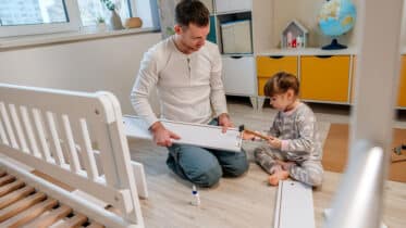 Vater und Tochter bauen ein Kinderbett selbst zusammen.