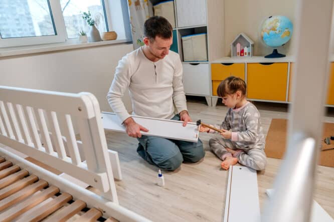 Vater und Tochter bauen ein Kinderbett selbst zusammen. 