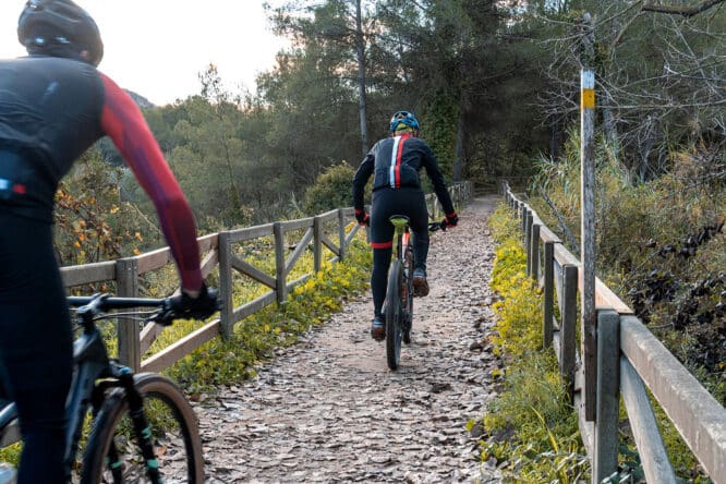 Radfahrer auf einem Weg mit Holzgeländer an den Seiten