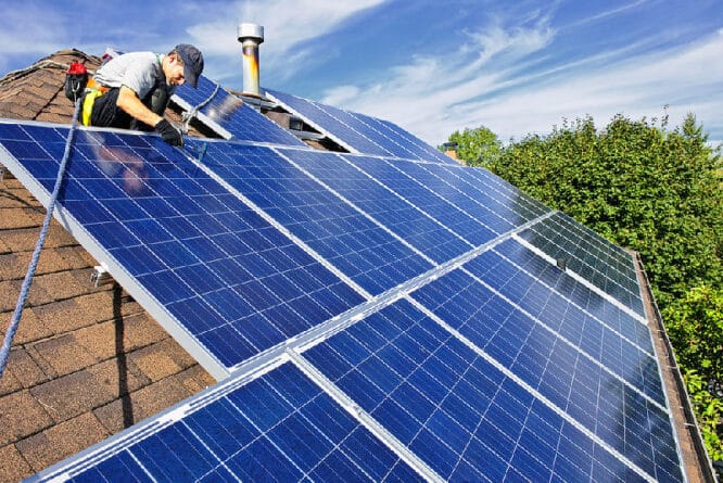Mann montiert Solarpaneele auf dem Dach.