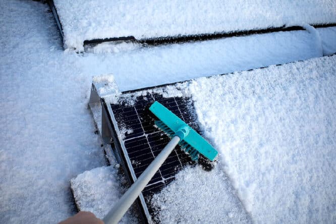 Sonnenkollektoren mit einem Besen vom Schnee befreien. 